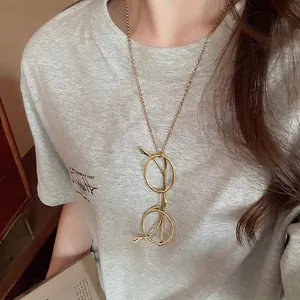 Minimalist gold eyeglasses pendant necklace for women worn on a casual grey t-shirt
