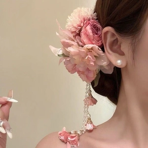 Nahaufnahme einer eleganten rosa Stoffblumen-Haarspange mit baumelnden Perlenquasten