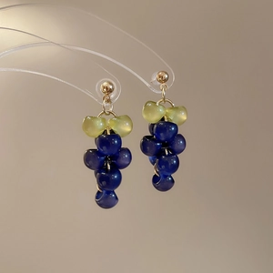 Macro detail of grape-shaped beaded tassel earrings with blue and green resin beads