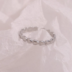 Macro shot of silver-colored heart-shaped linked open ring on white paper