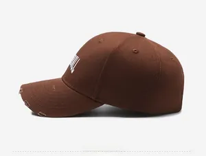 Detail view of distressed brown baseball cap with vintage embroidery and torn brim
