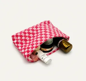 Detailed view of large knit checkerboard makeup bag with cosmetics inside for storage
