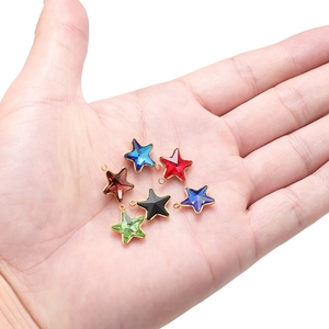 Set of colorful stainless steel star pendants with gold trim held in hand for scale
