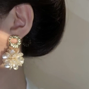 Close-up of gold plated flower earring with pearl luster worn by a model