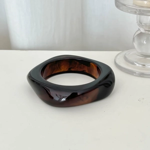 Macro shot of wide tortoiseshell resin bangle with deep amber marbled texture
