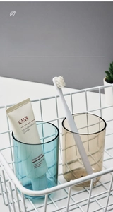 Detail of blue and brown transparent tooth mugs in a white metal basket