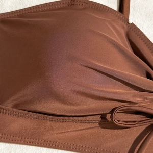 Detailed close-up of chocolate brown swimsuit fabric showing premium texture and stitching