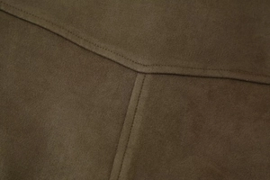 Detailed close-up of dark olive suede fabric texture and premium stitching on bomber jacket