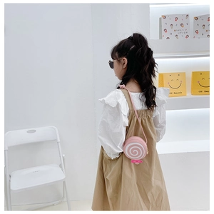 Girl wearing lollipop-shaped pink and white shoulder bag in a bright lifestyle setting