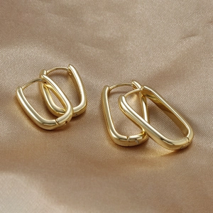 Detail of gold-plated U-shaped rectangular hoop earrings on smooth silk background