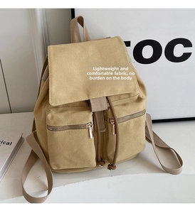 Detalle de mochila de lona caqui con cierre de cordón y dos bolsillos con cremallera