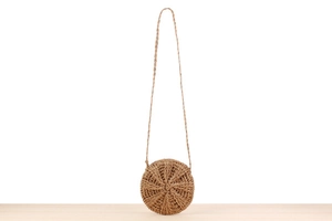 Detail of round straw crossbody bag with radial woven pattern and slim shoulder strap
