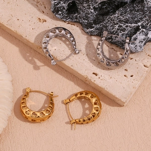 Detail of 18K gold and silver hollow heart U-shaped hoop earrings on stone base