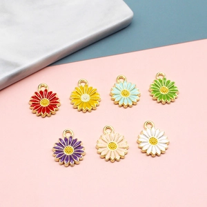 Close-up of seven colorful enamel daisy pendants with golden hanging loops for DIY crafts