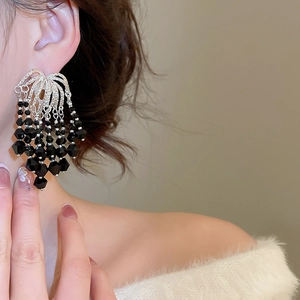 Detail view of ornate chandelier earrings with silver filigree and black faceted beads