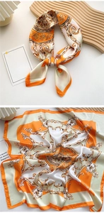 Detailed macro view of orange baroque satin scarf showing silk texture and golden patterns
