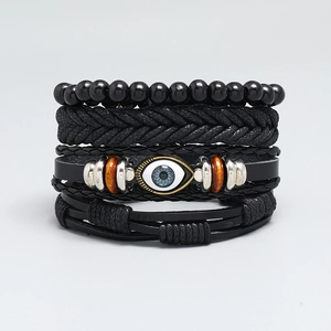 Detail of four-piece black leather bracelet set with blue evil eye and wooden beads