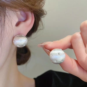 Macro detail of pearlescent ball stud earrings with sparkling rhinestone stars