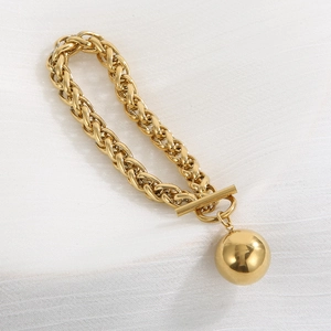 Detail of gold chunky cable link bracelet featuring a large ball charm and T-bar toggle clasp