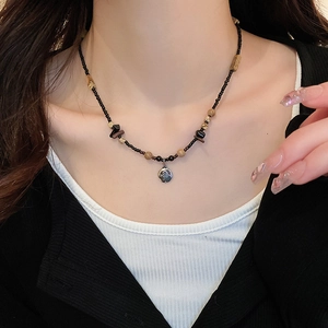 Detail of beaded necklace with butterfly pendant and natural stone accents on a model
