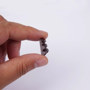 Realistic mini dark brown chocolate resin charm held by fingers on a white background