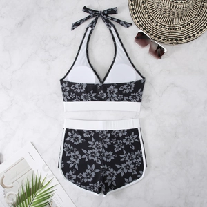 Flat lay of tropical floral bikini set with halter top and high-waisted shorts on marble