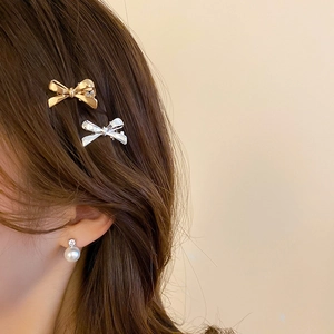 Close-up of elegant bow hair clips and pearl stud earring worn on a female model