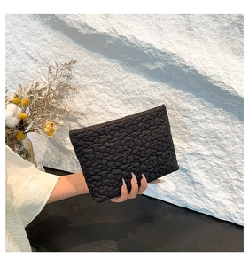 Close-up of black envelope clutch with quilted 3D floral texture and soft cotton material