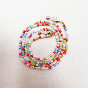 Macro view of colorful seed beads and faux pearls on eyewear chain with gold lobster clasp