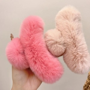 Detail of plush faux rabbit fur shark hair clips in pink and beige for winter hair styling