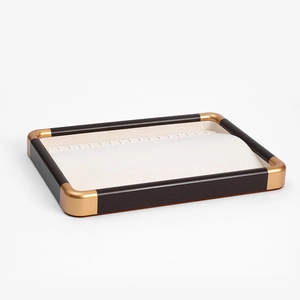 Macro view of walnut jewelry tray with cream velvet lining and gold accent hooks