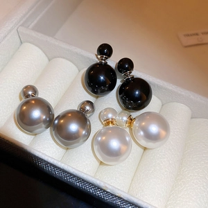 Detail of double-sided pearl stud earrings in black, silver, and white on velvet box