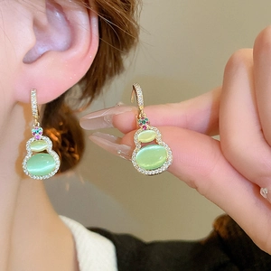 Close-up of gold-plated gourd earring with cat eye stone and cubic zirconia inlay