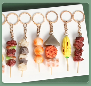 Dettaglio di portachiavi realistici in PVC con spiedini di cibo, mais e carne