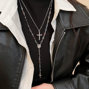 Detail of layered silver cross necklaces with colorful stones on black clothing