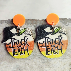 Close-up of apple shaped wooden Halloween earrings featuring Trick or Teach lettering