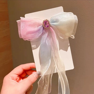 Detailed macro view of ombre organza hair bow with center purple gemstone and metal base