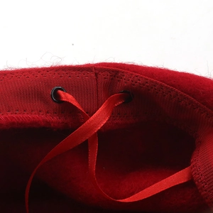 Detail of red wool beret interior featuring adjustable red ribbon and breathable sweatband