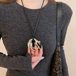 Detailed view of leopard pendant with rhinestones on a gold necklace worn by a model