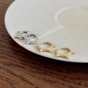 Detailed view of silver and gold spiked huggie earrings with diamond-encrusted accents
