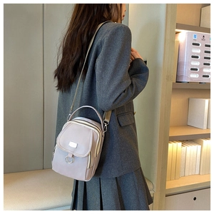 Close-up of light purple nylon crossbody bag with multiple zippers and silver ring detail