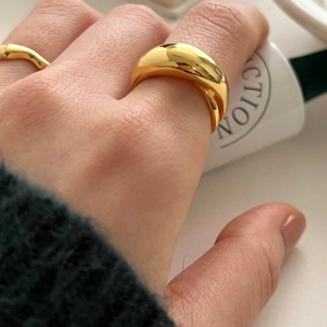 Close-up of a polished gold dome ring worn by a model for a stylish layered look