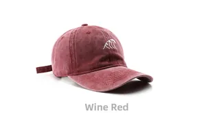 Detail of vintage washed burgundy baseball cap with intricate white wave embroidery