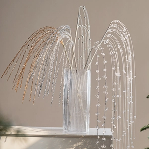 Artificial Christmas tree branch ornaments with glitter and beads in glass vase