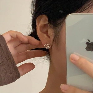 Close-up of minimalist silver knot earrings showing elegant spiral design on ear