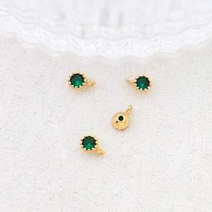 Detail of round green zircon charms with gold-plated settings for DIY jewelry making