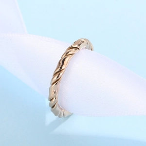 Detailed view of a gold twisted minimalist ring showcased on a white stand