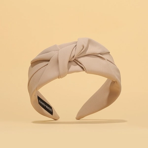 Detailed close-up of beige fabric pleated headband with a hand made internal label