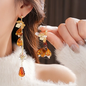 Detailed view of amber tassel earrings with golden floral accents worn by a model