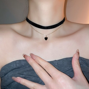 Detail of double-layer velvet choker with golden chain and black heart pendant necklace